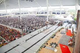 A stadium-scale covered gathering seen from above, seating filled to the edges.
